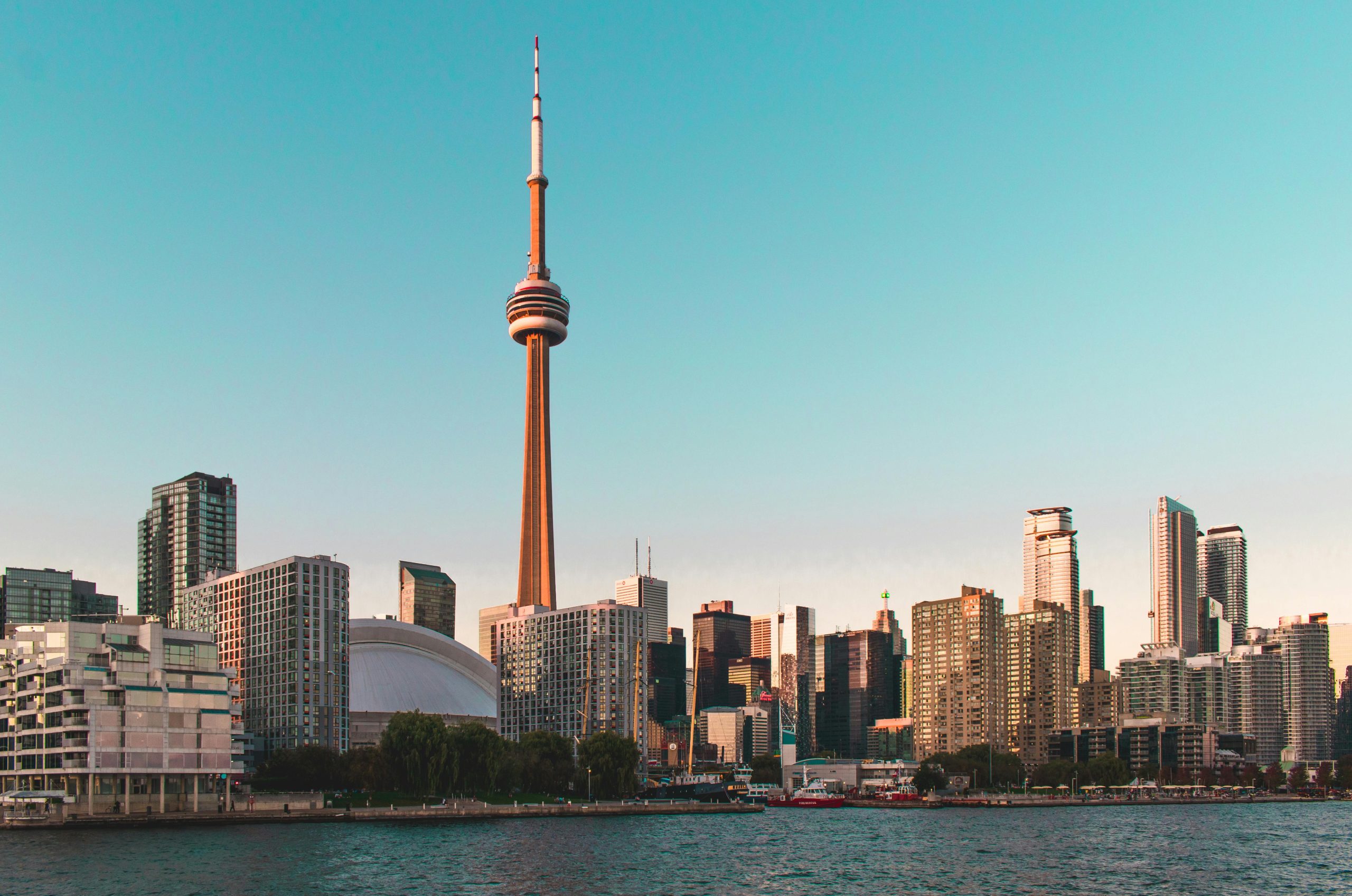 Skyline of Toronto featuring the CN Tower and surrounding buildings at sunset.