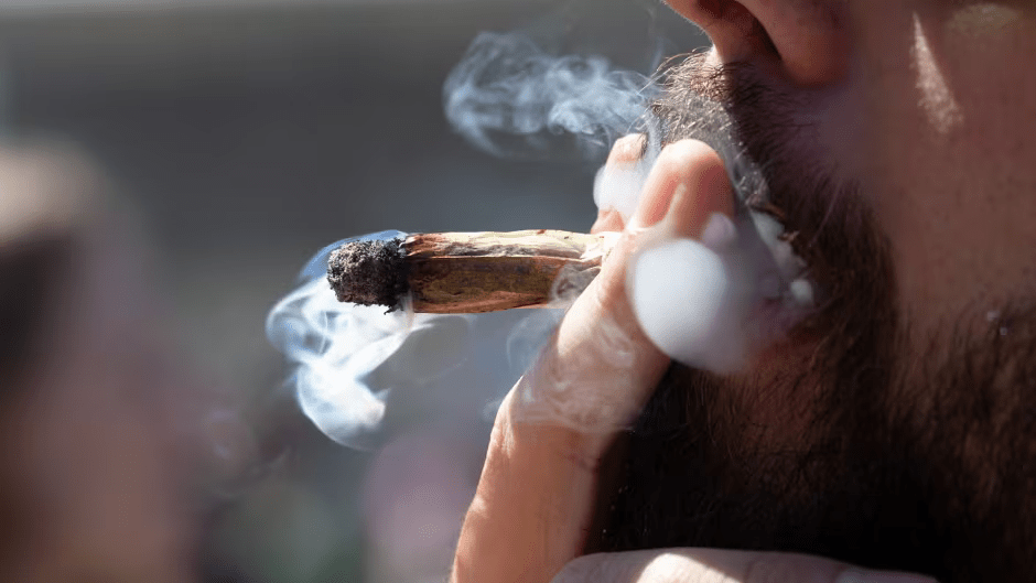 Close-up of a person smoking a marijuana joint.